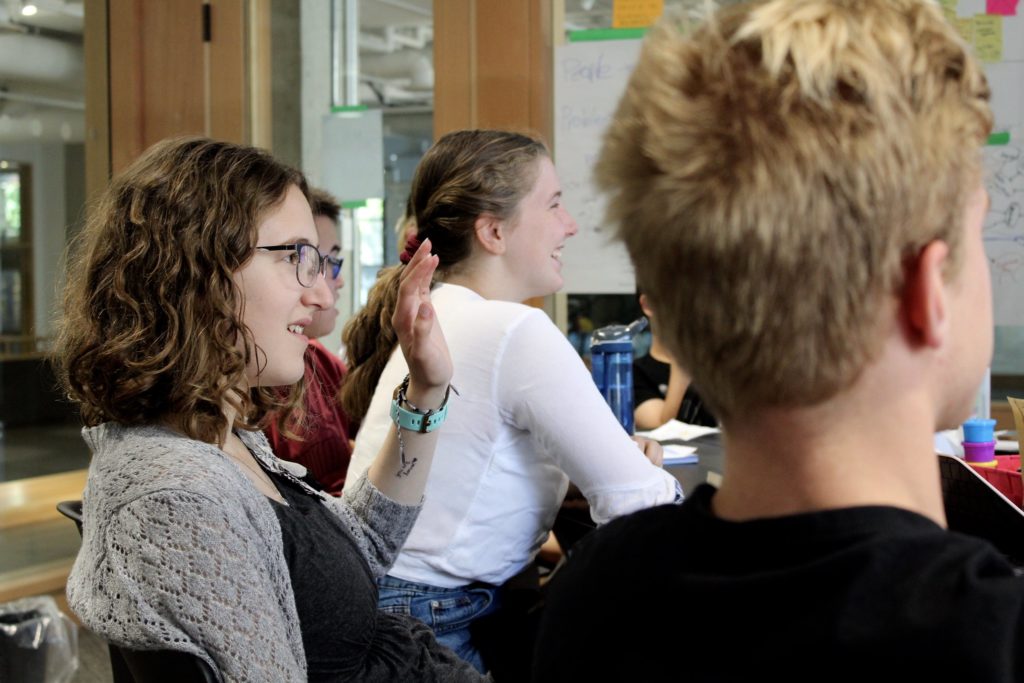 student raises her hand in a classroom for teachers